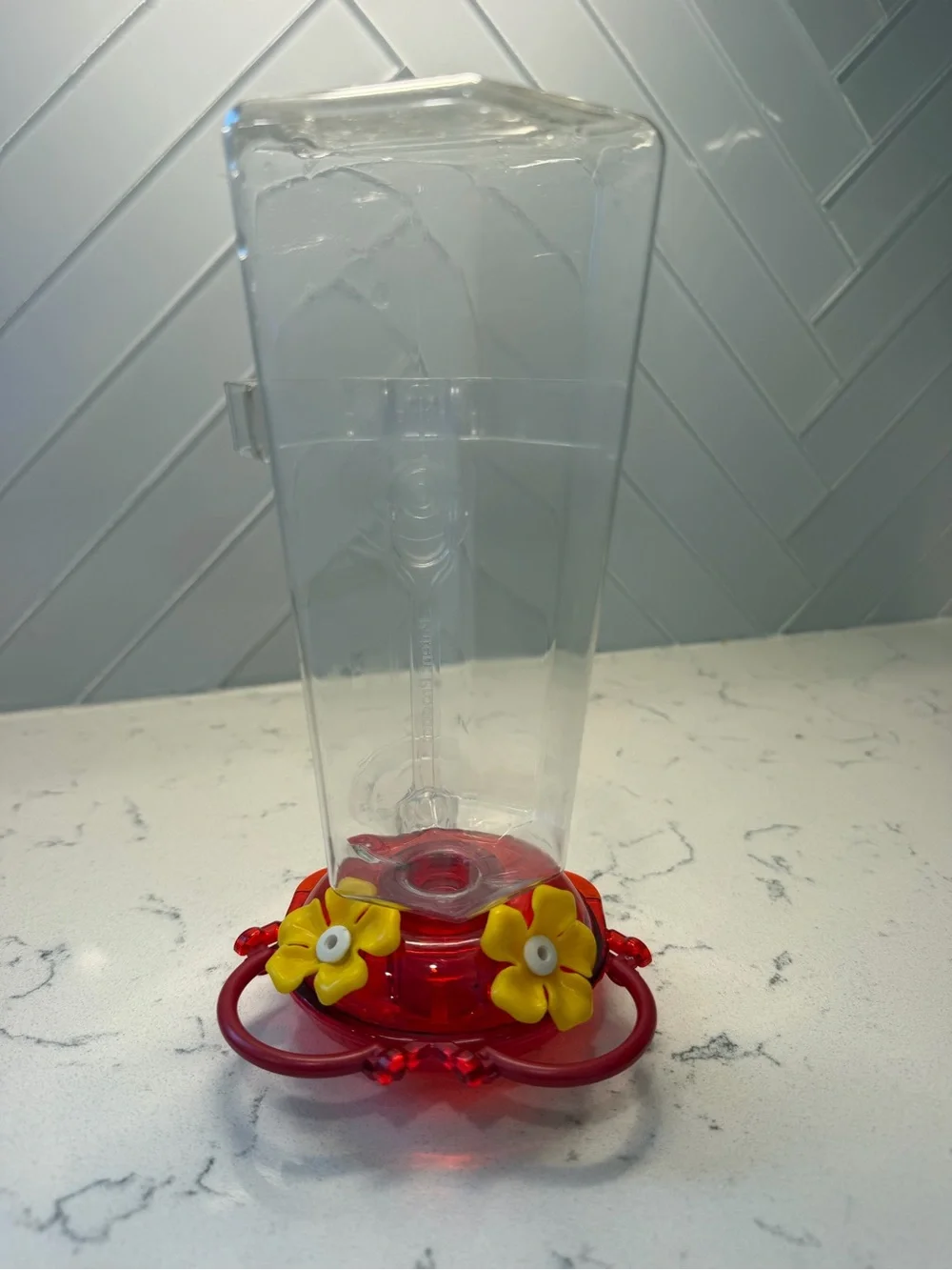 Clear Plastic Hummingbird Feeder with Red Base and Yellow Flowers